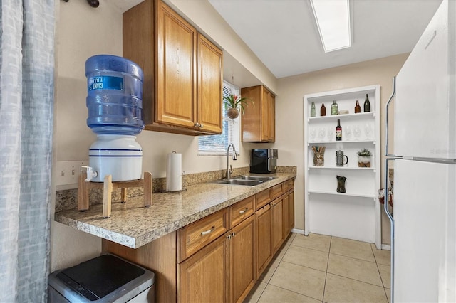 kitchen featuring white refrigerator, light tile patterned floors, and sink