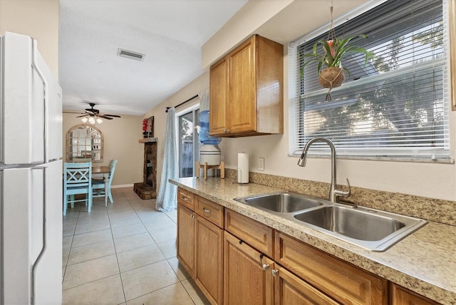 kitchen with light tile patterned floors, white fridge, ceiling fan, and sink