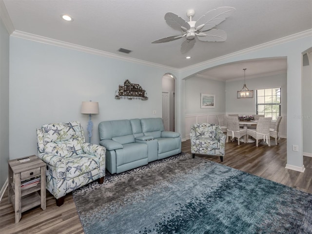 living room with hardwood / wood-style flooring, ceiling fan with notable chandelier, and ornamental molding