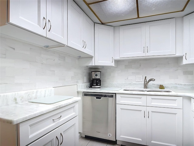 kitchen with dishwasher, white cabinets, sink, light tile patterned floors, and backsplash