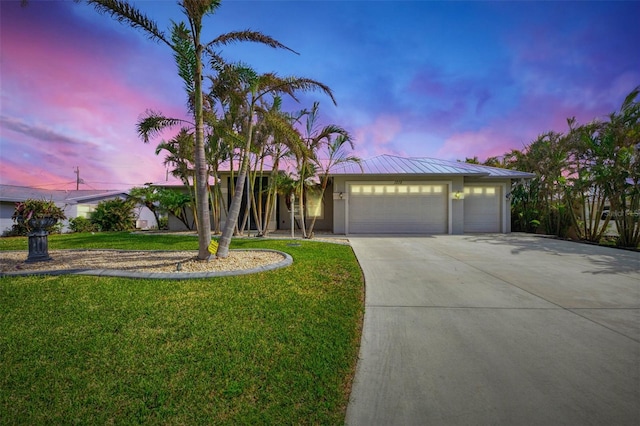 view of front of property with a garage and a yard