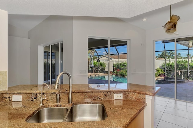 1219 Nantucket Rd, Venice, FL 34293 - kitchen with a sink, lofted ceiling, light tile patterned floors, plenty of natural light, and light stone counters