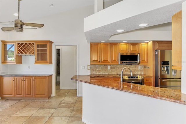 1219 Nantucket Rd, Venice, FL 34293 - kitchen with appliances with stainless steel finishes, stone counters, a ceiling fan, tasteful backsplash, and glass insert cabinets