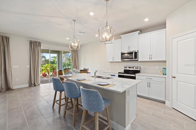 kitchen with a kitchen island with sink, hanging light fixtures, sink, white cabinetry, and stainless steel appliances