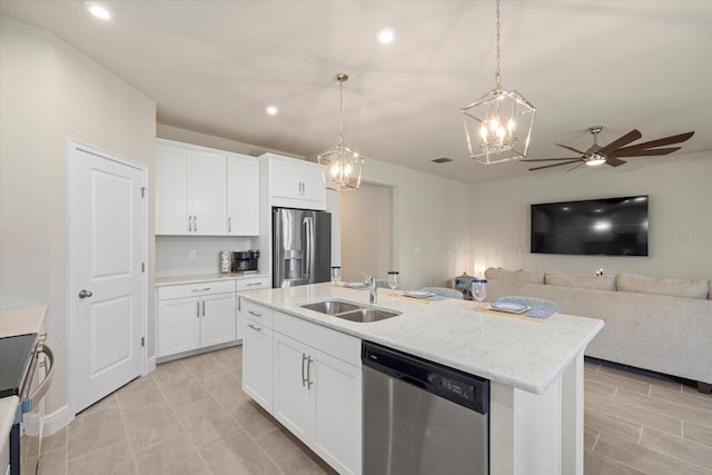 kitchen with appliances with stainless steel finishes, white cabinetry, hanging light fixtures, and a kitchen island with sink