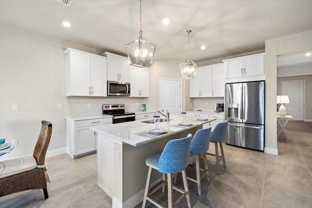 11925 Bohemian Pl, Venice, FL 34293 - kitchen featuring appliances with stainless steel finishes, a sink, a center island with sink, a kitchen bar, and white cabinets