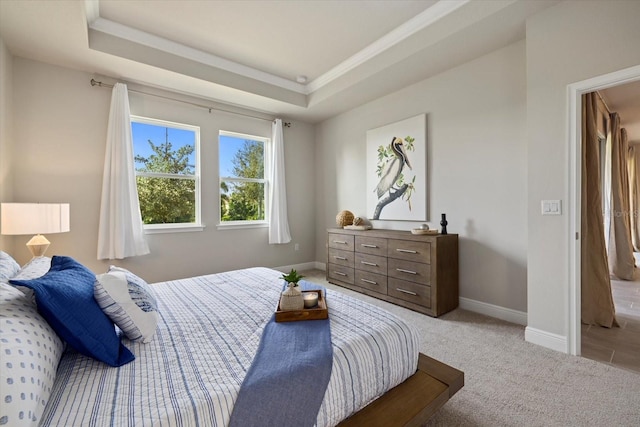 bedroom with light colored carpet and a tray ceiling