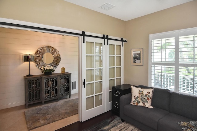 living room with dark tile patterned flooring and a barn door