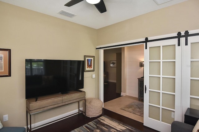 living room featuring ceiling fan, wood-type flooring, and a barn door