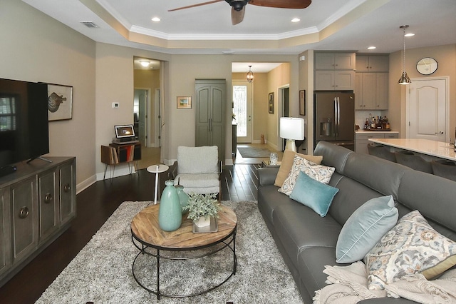 living room featuring crown molding, a raised ceiling, dark hardwood / wood-style floors, and ceiling fan