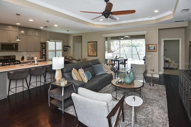 living room featuring ceiling fan, a wealth of natural light, dark hardwood / wood-style floors, and a tray ceiling