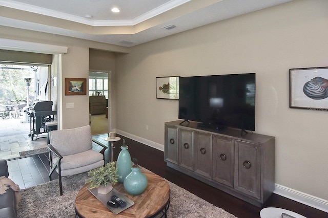 living room with dark wood-type flooring, crown molding, and a tray ceiling