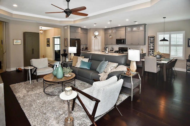 living room with dark hardwood / wood-style flooring, ceiling fan, crown molding, and a raised ceiling