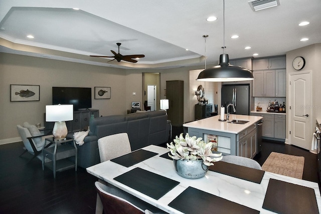 dining space with ornamental molding, dark hardwood / wood-style flooring, sink, a tray ceiling, and ceiling fan