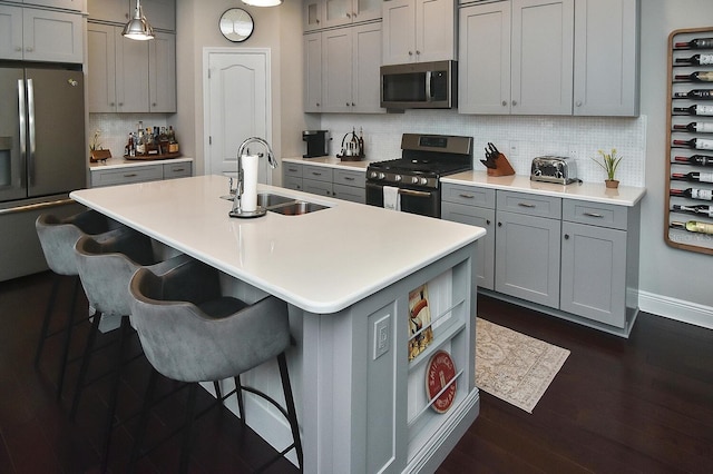 kitchen featuring a kitchen island with sink, decorative backsplash, stainless steel appliances, and sink