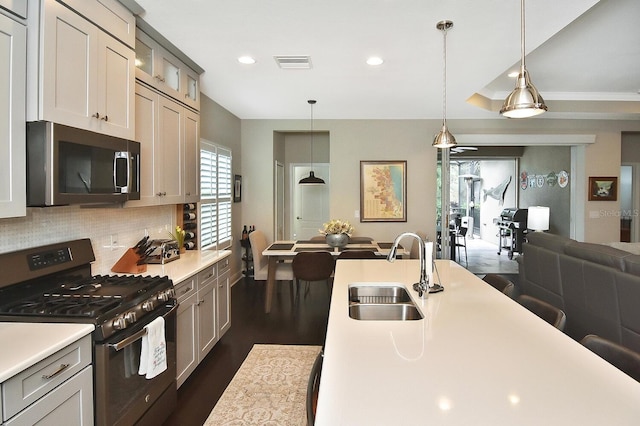 kitchen with appliances with stainless steel finishes, decorative light fixtures, sink, decorative backsplash, and dark wood-type flooring