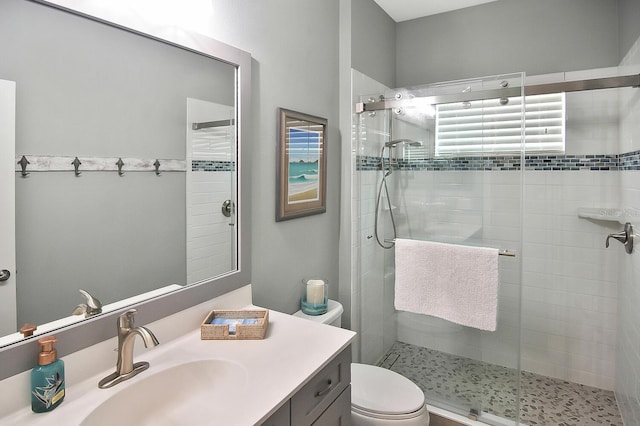 bathroom with a shower with shower door, vanity, and toilet