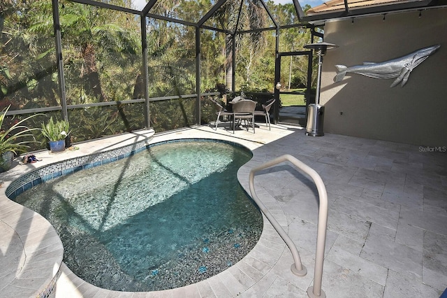 view of swimming pool featuring glass enclosure and a patio area