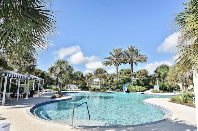 view of pool with a water slide and a patio area