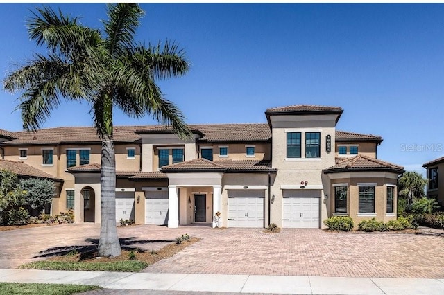 view of front of home featuring a garage, driveway, a tile roof, and stucco siding