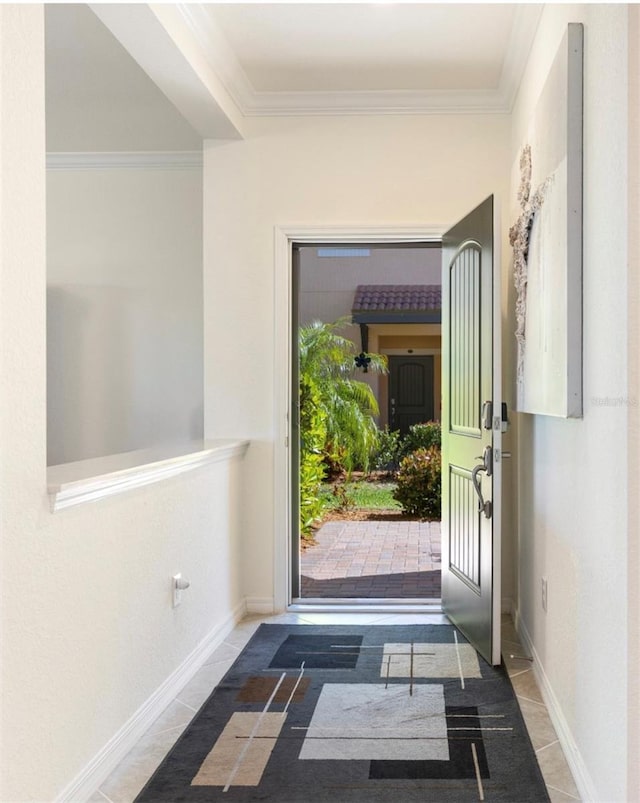 doorway with ornamental molding, dark tile patterned floors, and baseboards