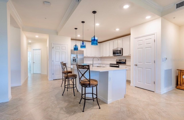 kitchen featuring a center island with sink, light countertops, visible vents, appliances with stainless steel finishes, and white cabinets