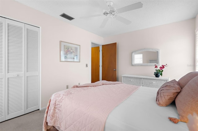 bedroom featuring ceiling fan, a textured ceiling, light carpet, and a closet