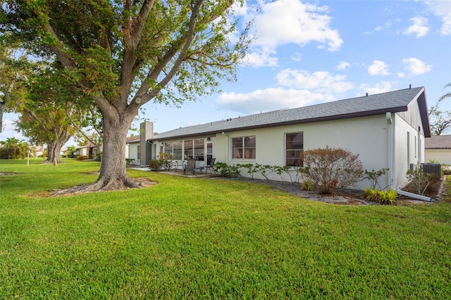 605 Apple Ln, Englewood, FL 34223 - rear view of property featuring a lawn, stucco siding, a patio area, and a chimney