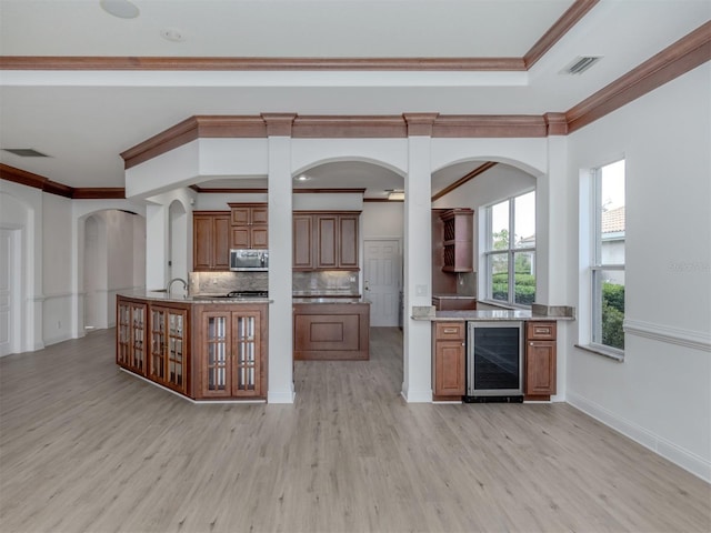 kitchen with decorative backsplash, light wood-type flooring, beverage cooler, and ornamental molding