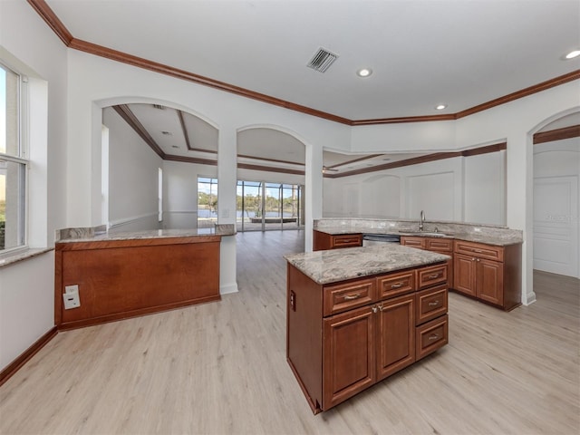 kitchen featuring light stone countertops, crown molding, sink, a center island, and light hardwood / wood-style floors