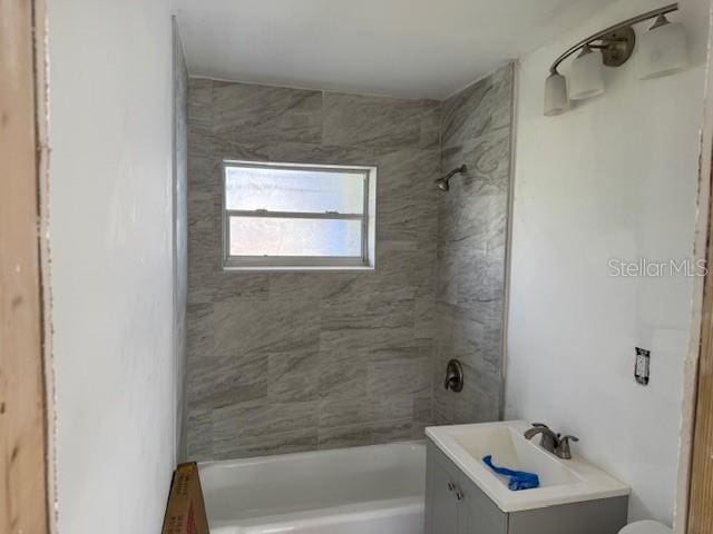 full bathroom featuring vanity, tiled shower / bath combo, and toilet