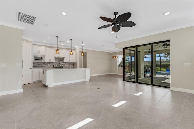 kitchen featuring stainless steel appliances, tasteful backsplash, decorative light fixtures, a center island with sink, and white cabinets