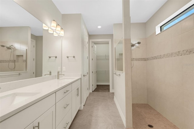 bathroom featuring tiled shower, vanity, and tile patterned flooring