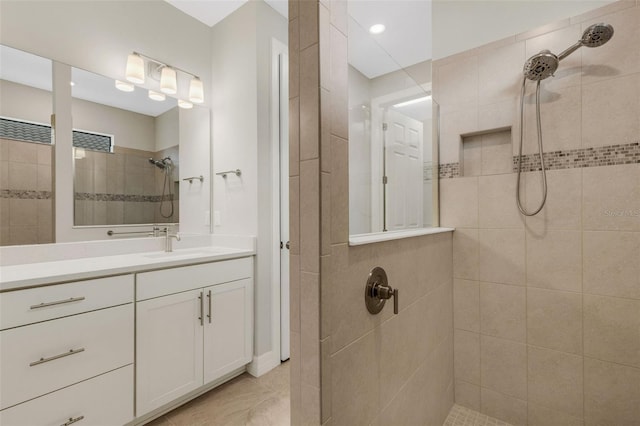 bathroom with a tile shower, tile patterned flooring, and vanity