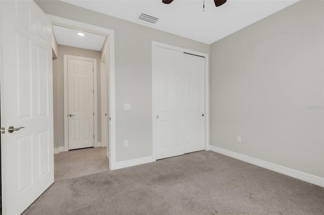 unfurnished bedroom with ceiling fan, light colored carpet, and a closet