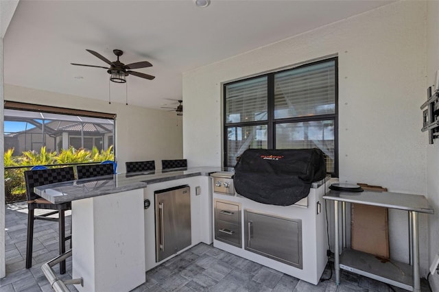 view of patio featuring ceiling fan, exterior kitchen, a lanai, exterior bar, and area for grilling