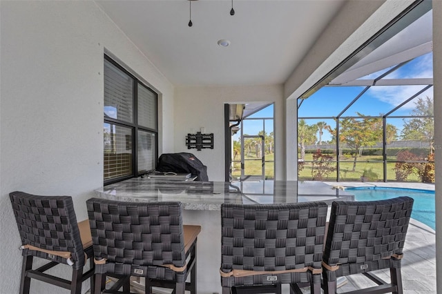 view of patio featuring area for grilling, glass enclosure, and an outdoor bar