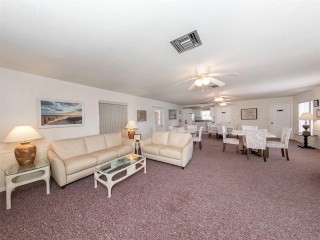 carpeted living room with a textured ceiling and ceiling fan