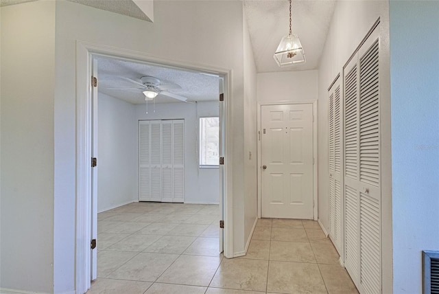 corridor featuring a textured ceiling and light tile patterned floors