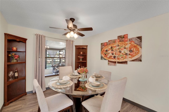 dining area featuring ceiling fan, light hardwood / wood-style floors, and a textured ceiling