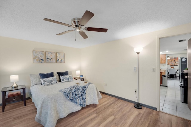 bedroom featuring ceiling fan, light wood-type flooring, and a textured ceiling