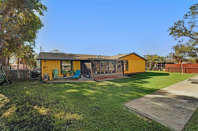 rear view of house with a patio area, a sunroom, and a yard