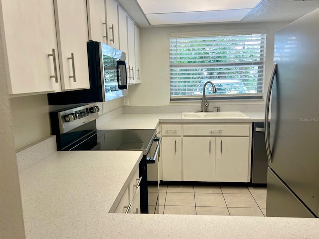 kitchen featuring white cabinetry, sink, light tile patterned floors, and stainless steel appliances