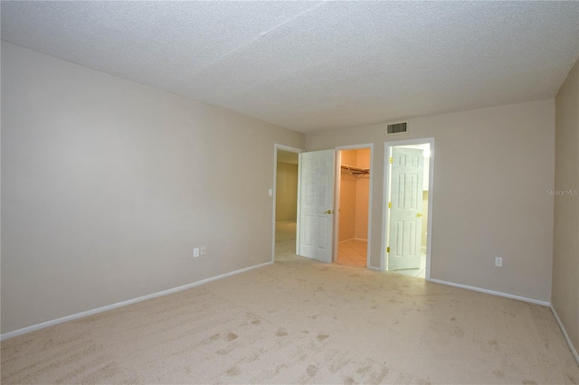 empty room with light colored carpet and a textured ceiling