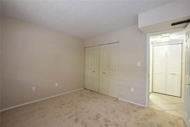 unfurnished bedroom with a closet, light colored carpet, and a textured ceiling