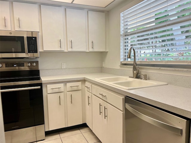 kitchen featuring sink, white cabinets, light tile patterned floors, and appliances with stainless steel finishes