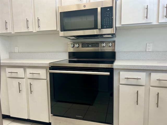 kitchen with white cabinets, light tile patterned floors, and stainless steel appliances