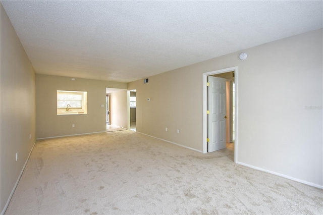 unfurnished room with light colored carpet and a textured ceiling