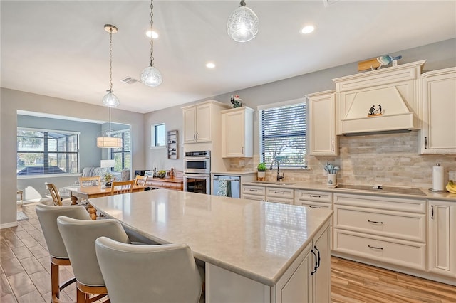 kitchen featuring stainless steel appliances, sink, pendant lighting, a center island, and light hardwood / wood-style floors