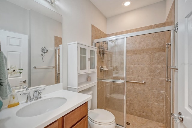 bathroom featuring vanity, toilet, and a shower with door